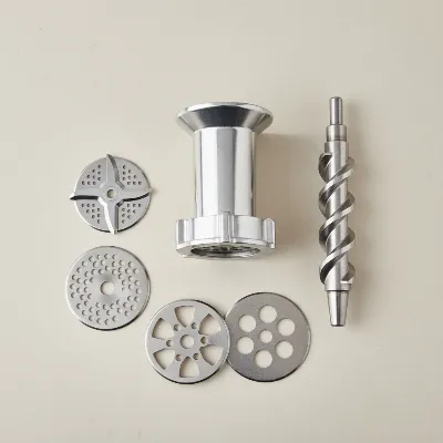 Various high-quality stainless steel meat grinder components like blades, plates, and auger laid out on a kitchen counter.